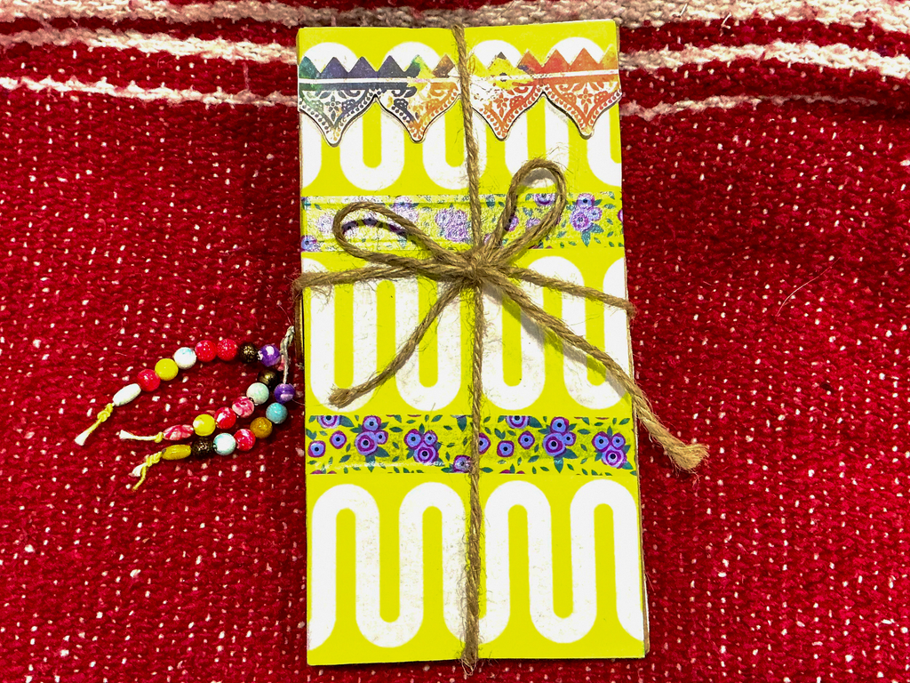 Festival Junk Journal Cover with colorful paper flags tied with twine.