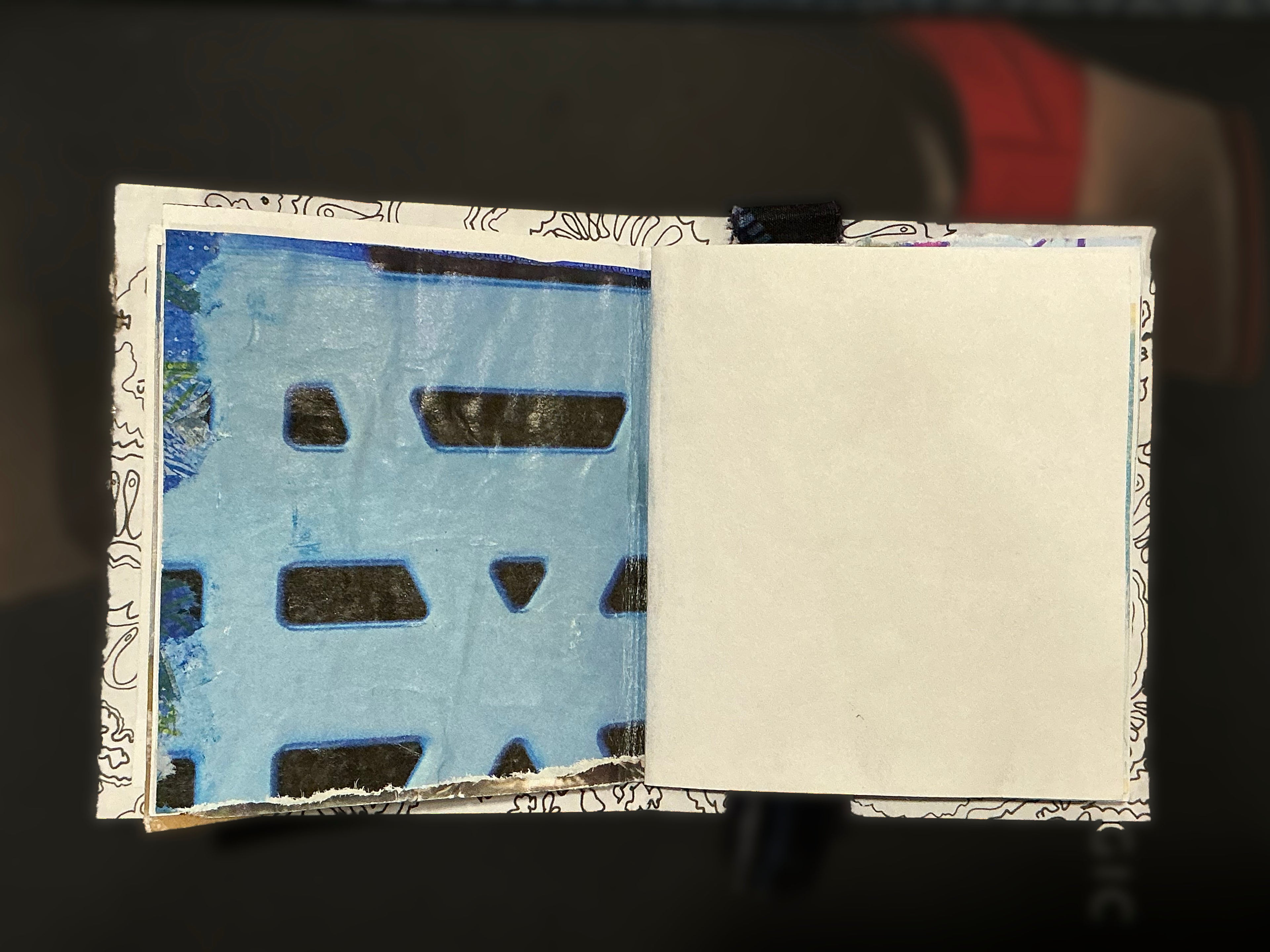 Open book with a blue watercolor page and white text pages on a dark background